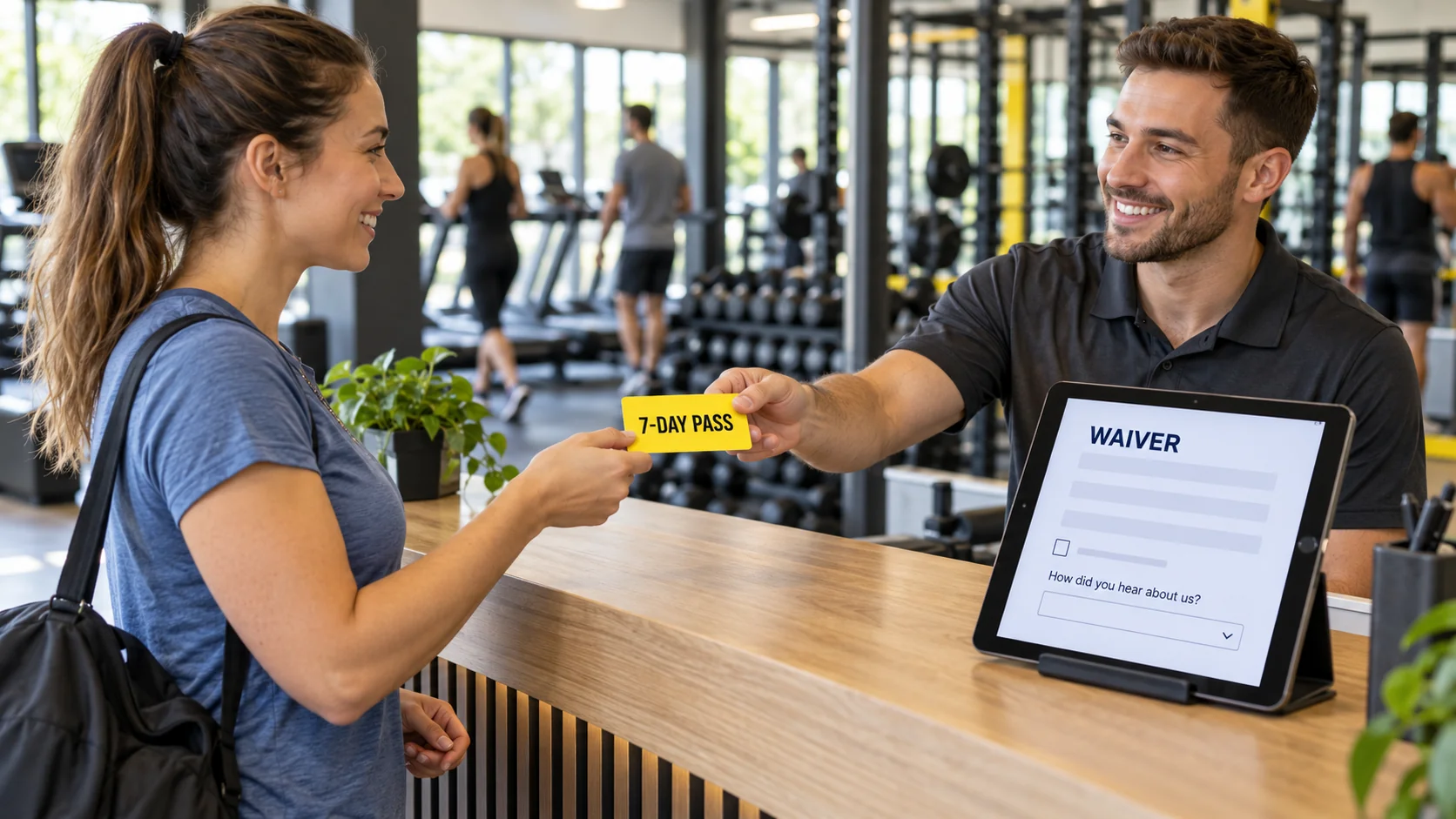 Gym membership sales start at the front desk: a first-time visitor is handed a free 7-day pass while the waiver tablet asks how they heard about the gym